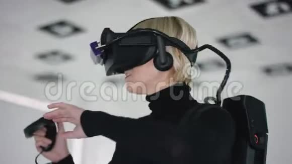 一名成年女子戴着虚拟现实眼镜手持一个控制器并在空中使用它作为视频游戏视频的预览图