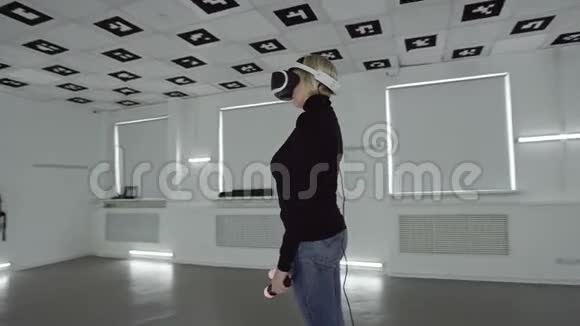 年轻女子戴着vr耳机在一个充满白色霓虹灯的空房间里拿着控制器追踪弧射视频的预览图