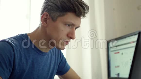 帅哥在家看笔记本电脑的情感肖像视频的预览图