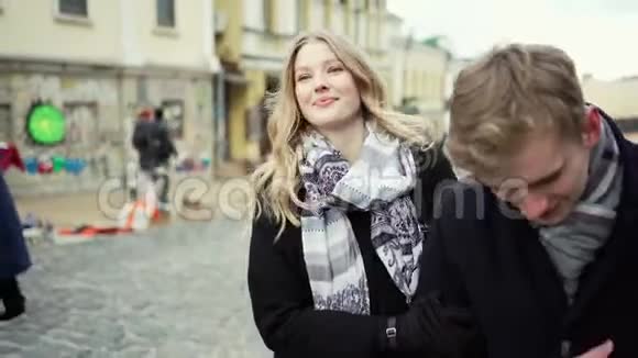 年轻漂亮的金发美女夫妇走在城市的街道上微笑着看着对方视频的预览图