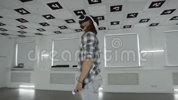 一个穿着vr耳机的年轻人做手势在充满白色霓虹灯照明的空玩室里使用控制器视频的预览图