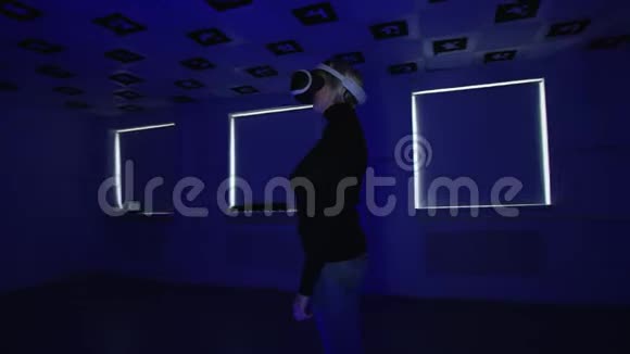 在playstation虚拟现实耳机里年轻女子站在一个空的游戏室里里面闪烁着红色和蓝色的霓虹灯视频的预览图