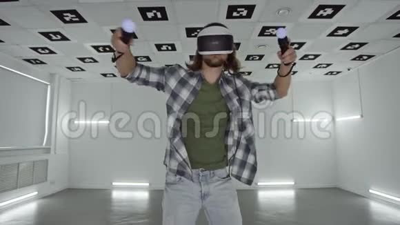 虚拟现实中戴眼镜的年轻人在一个充满白色霓虹灯照明的空玩室里用电子游戏跳舞视频的预览图