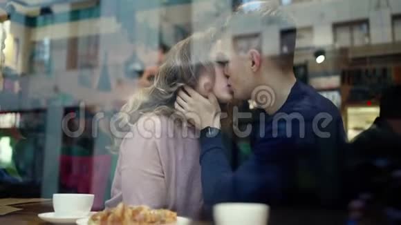 可爱的幸福浪漫夫妇拥抱和亲吻而坐在窗口的咖啡馆年轻人温柔地拥抱和视频的预览图