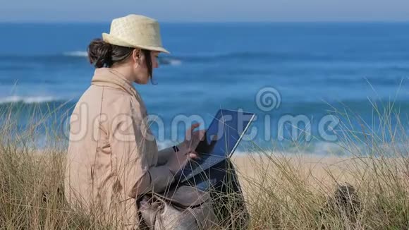 在阳光明媚的海滩上女人在笔记本上发短信视频的预览图