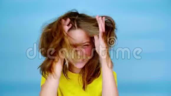 穿着黄色T恤的快乐少女正在大笑双手捂住脸看着镜头视频的预览图