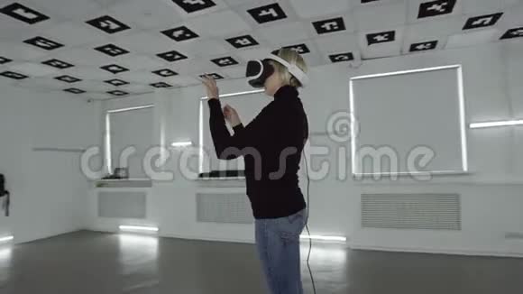 年轻女子戴着psvr耳机在一个充满白色霓虹灯的空房间里做手势跟踪弧视频的预览图