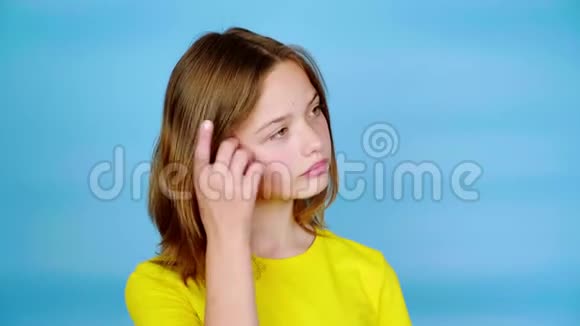 穿着黄色t恤的快乐少女一只手挽直头发摆姿势看着镜头视频的预览图
