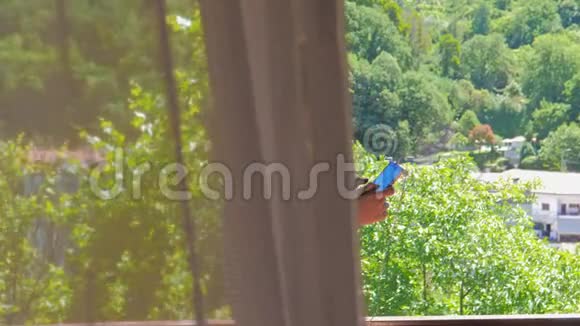 阳台上的年轻女子通过电话听音乐视频的预览图