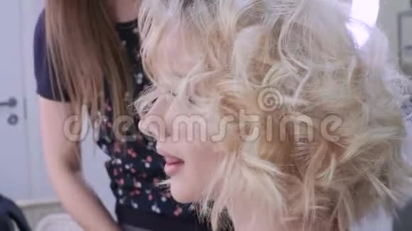 一位金发女人在和发型师的会议上理发有卷发的迷人造型视频的预览图