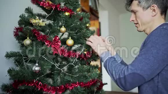 快乐的微笑男人手把球挂在圣诞树上视频的预览图