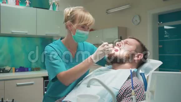 牙医检查病人牙齿解释他的程序视频的预览图