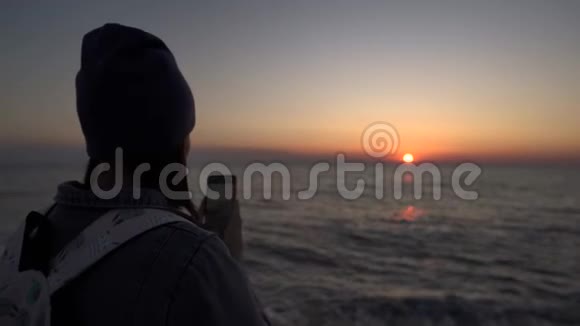 一个旅游女孩在手机上拍照日落日落时的剪影视频的预览图
