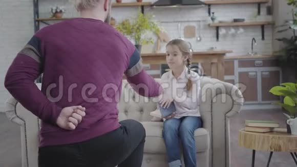 成年白种人单膝站立并握住女儿的手十几岁的女孩收起书本站起来视频的预览图