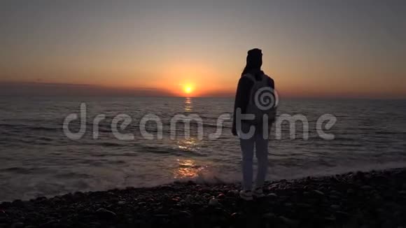 一个旅游女孩欣赏海滩上的日落浪漫的场景剪影视频的预览图