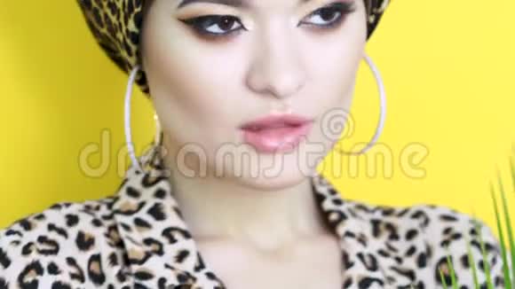 一个漂亮的年轻女人穿着一件用黄色豹纹织物做成的时髦头巾视频的预览图