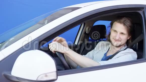 满意的人正在看外面的汽车镜子自鸣得意的年轻人正在抚摸他的头发唱着一首歌视频的预览图