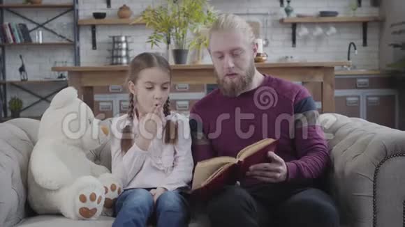 奇怪的白人女孩听父亲读她的书的肖像积极的男人抚摸女儿鼻子视频的预览图