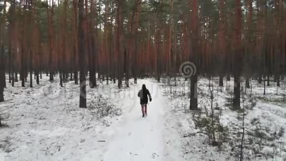 一个拿着公文包的人在冬天的树林里跑空中观景视频的预览图