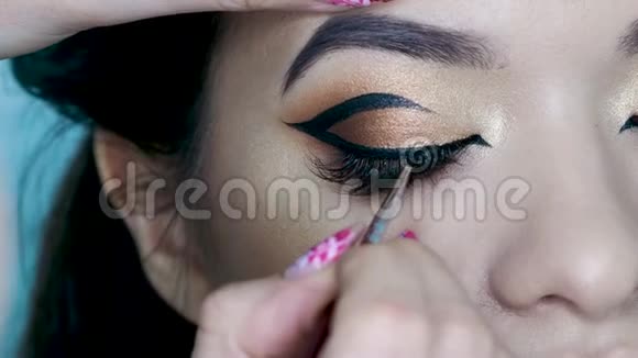 美容院化妆师做晚妆美丽的眼睛金色的眼影视频的预览图