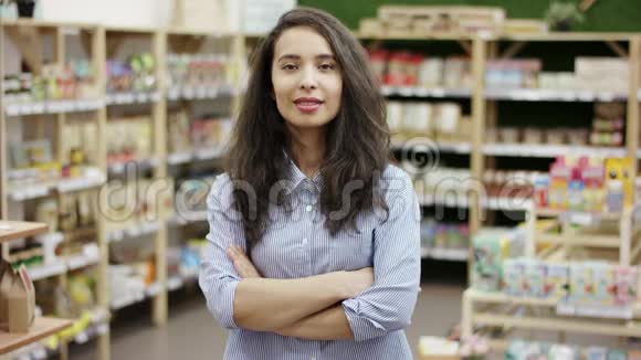 在超市背景下一个漂亮的白种人女孩交叉着双臂站着在镜头前笑容满面视频的预览图