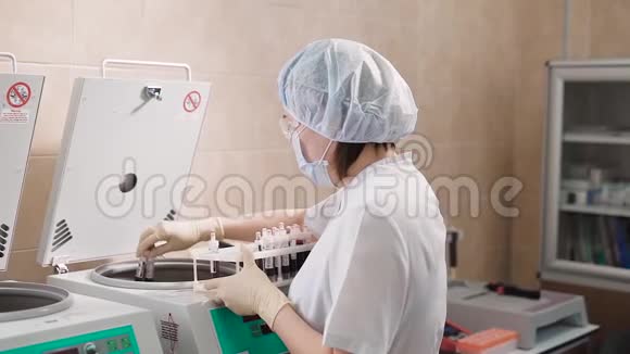 一位穿着白色实验室外套和卫生手套的成年女医生将血液测试储存在离心机的试管中视频的预览图