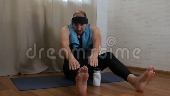 有趣的胖子正试图在地毯上做瑜伽练习穿紧身衣服的男性瑜伽士视频的预览图