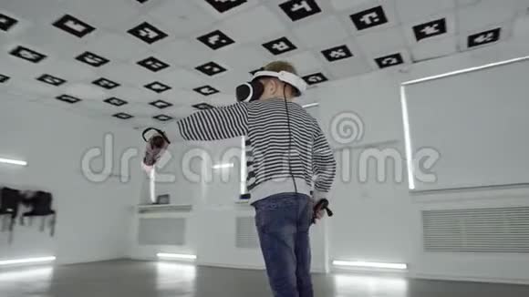 虚拟现实耳机里的小男孩正和控制器在一个充满白光的空玩室里挥手视频的预览图