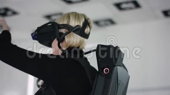 一位戴着虚拟现实耳机的成年女性手持控制器在一个空荡荡的游戏室里玩游戏的特写镜头视频的预览图