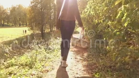 一个年轻的黑发女人拿着篮子穿过秋天的树林的慢动作稳定的视频视频的预览图