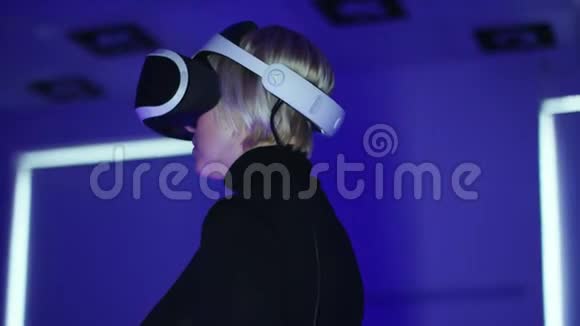 一个年轻女子在一个游戏室里站着一个虚拟现实耳机上下移动耳机视频的预览图