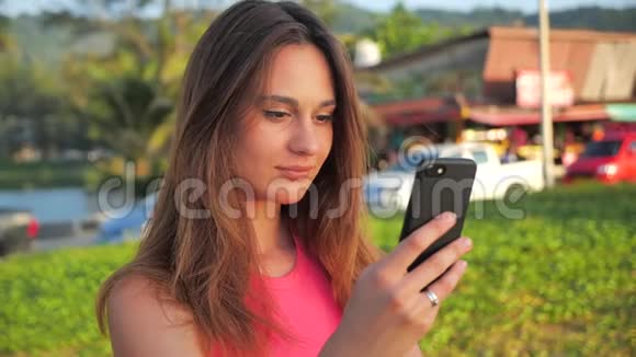 特写年轻女子穿粉色短衫的肖像她站在背景中的网站棕榈女性使用视频的预览图