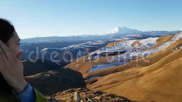 一个满意的女孩旅行者在明亮的埃尔布鲁斯山的背景下自拍布鲁内特高加索之行视频的预览图