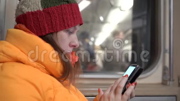 一个女人拿着手机坐在地铁里她读了些东西视频的预览图