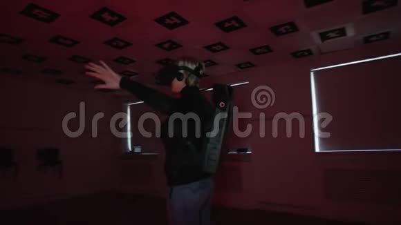 一位成年女性正在虚拟现实游戏中她戴着vr耳机站在闪烁的霓虹灯的游戏室里视频的预览图