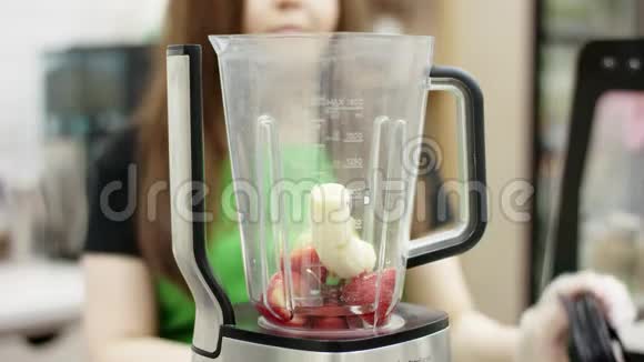 酒保把盖子盖在搅拌机上里面有水果和其他食材并把它锁起来准备做美味的冰沙视频的预览图