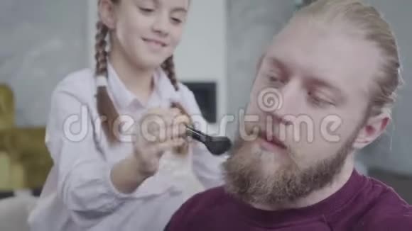 年轻的白种人精疲力竭的男子推开女儿的手的特写肖像她是一个十几岁的女孩她梳着他的胡子视频的预览图