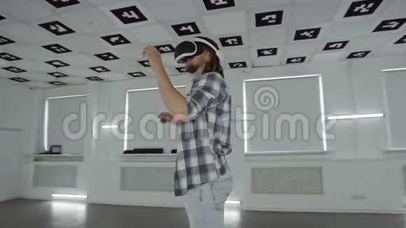 一个戴着虚拟现实眼镜的年轻人在一个充满白色霓虹灯的空玩室里用电子游戏做手势视频的预览图