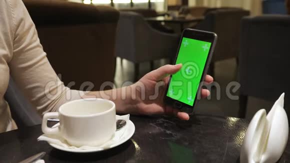 女孩手在咖啡馆里用绿色屏幕透过一个传感器电话视频的预览图