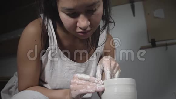 亚洲女性陶工在陶工x27的车轮上塑造陶工泥壶视频的预览图
