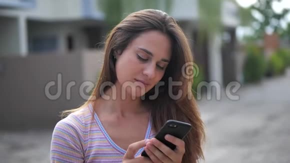 迷人的年轻女性在阳光明媚的城市街道上散步与朋友聊天在户外使用手机城市视频的预览图