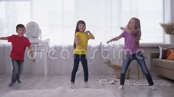 在一个白色的房间里穿着多种颜色的t恤跳舞的孩子们在度假时在明亮的窗户后面玩得很开心视频的预览图