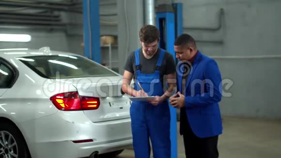 慢动作机械师和车主讨论汽车修理的价格视频的预览图