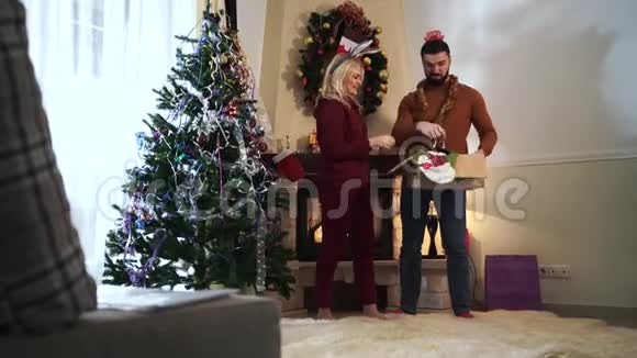 快乐的白种人男人和女人在新年前夕在家里玩丈夫和妻子在圣诞装饰上挂视频的预览图