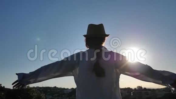 女人站在上面看着城市在黎明时举起双手对着太阳视频的预览图