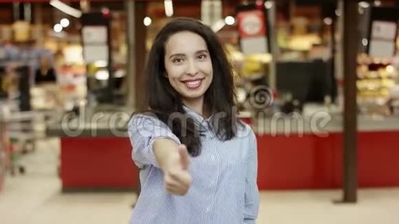 超市里的一位年轻可爱的女士先用右手竖起大拇指然后用左手然后用双手视频的预览图