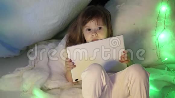 孩子们晚上在孩子们房间里看PDA上的卡通片可爱的小女孩沙发上有一台平板电脑视频的预览图