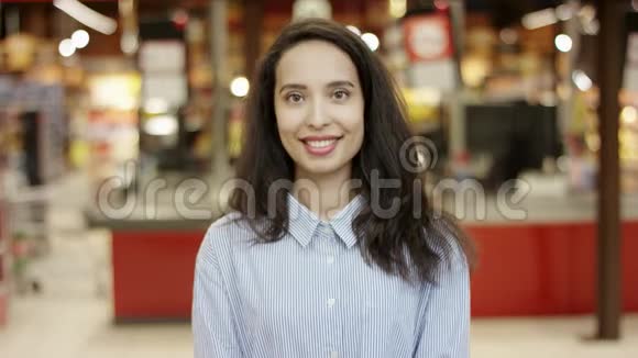 在超市里一个年轻漂亮的女孩在镜头前露出灿烂的笑容穿着白色和白色的衣服视频的预览图