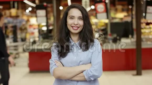 一张美丽的年轻女孩站在超市的肖像胸前交叉着双臂直视着镜头视频的预览图