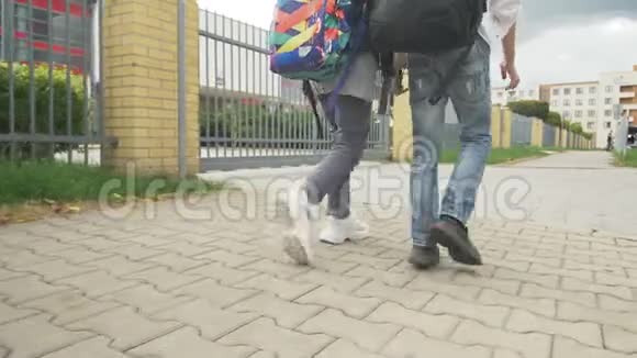 少年女孩和男孩带着背包在人行道上步行上学脚的特写慢动作录像视频的预览图
